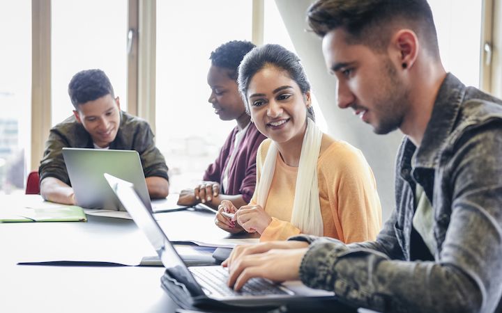 Diverse colleagues talking and looking at their computers