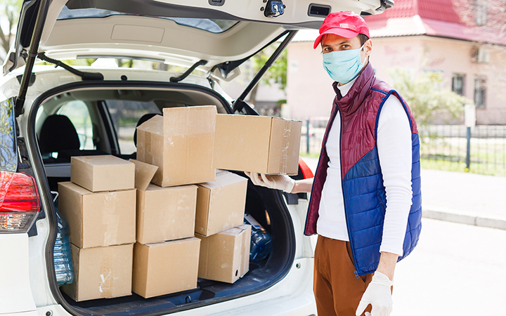 volunteer unpacks food donations in car