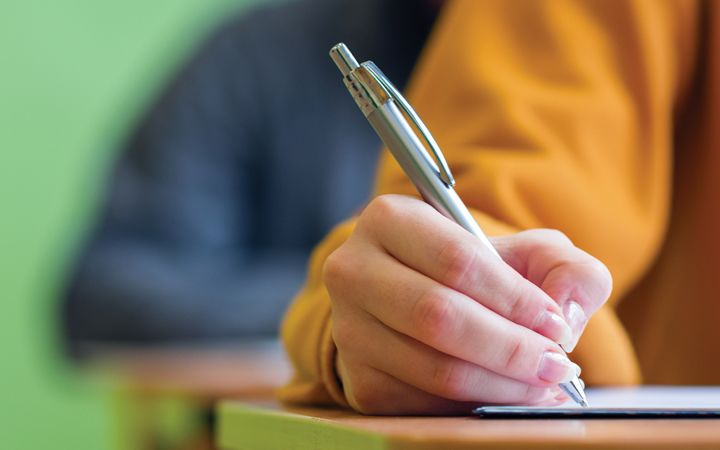 Hand holding pen, writing in class