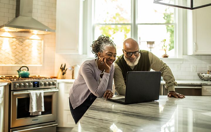 Couple in kitchen looking at computer