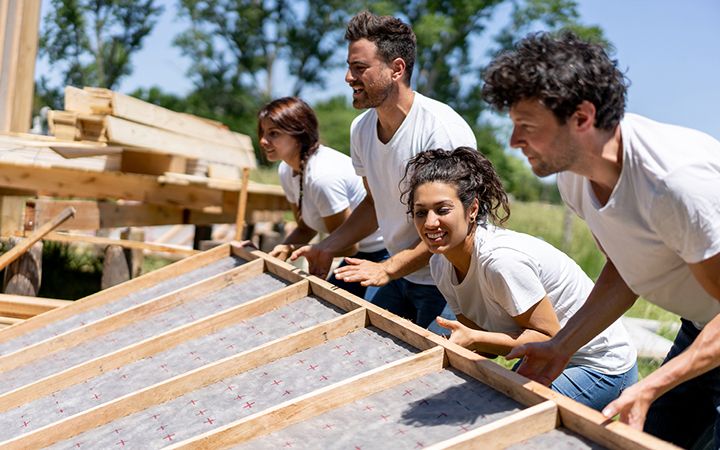 A group of people lifting a wood wall