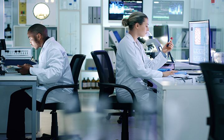 Employees in lab coats working at computers