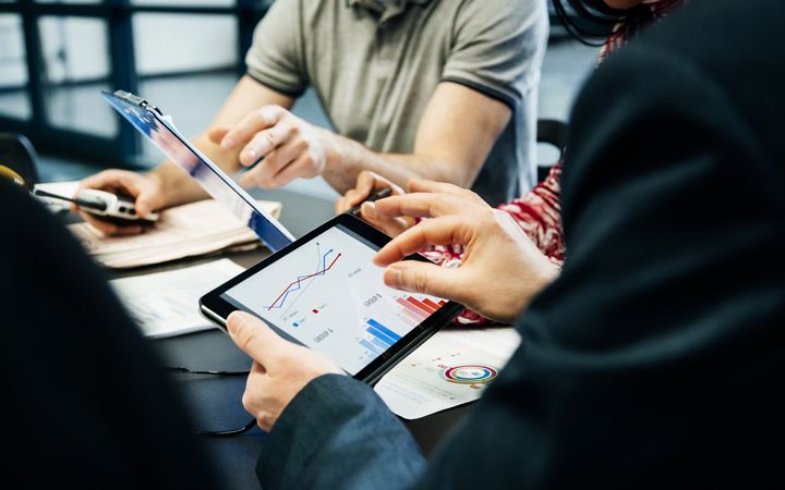 group of people using tablets to zoom in on data