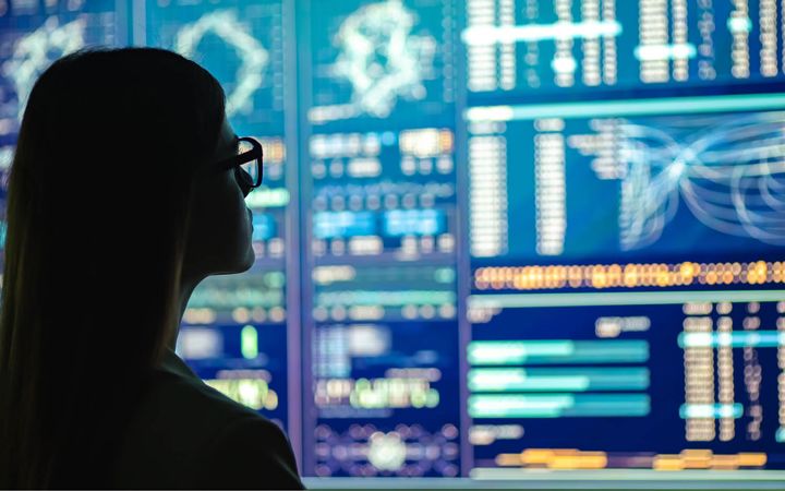 Women looking over disaster recovery plan analytics on digital screens