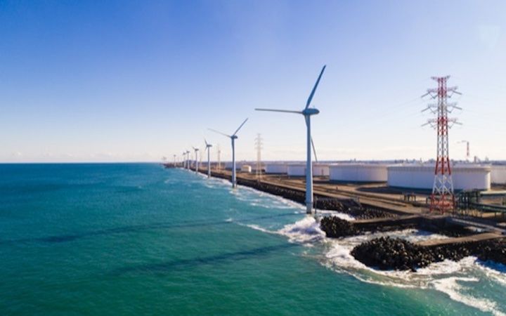 Windmills spinning next to body of water