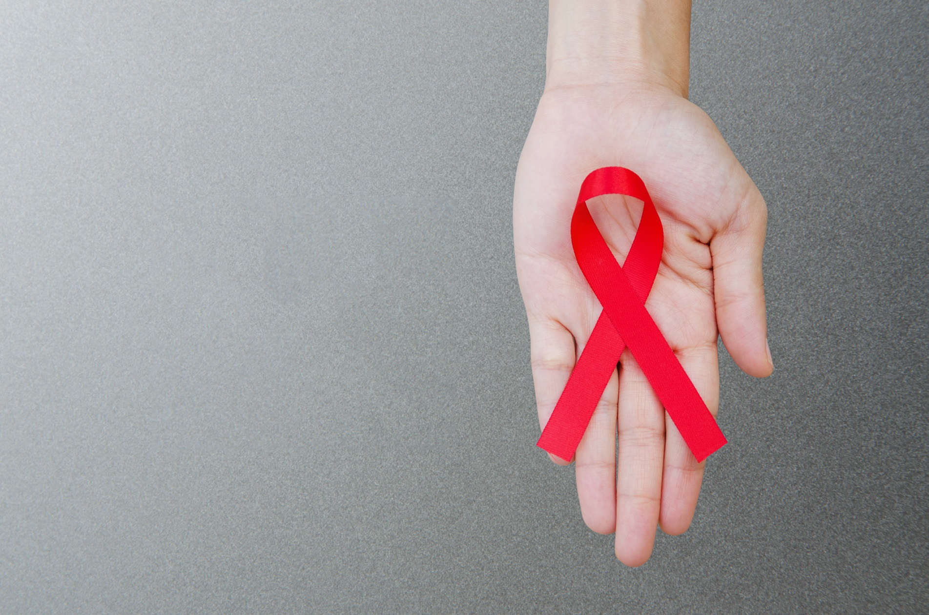 Hand holding AIDS awareness ribbon