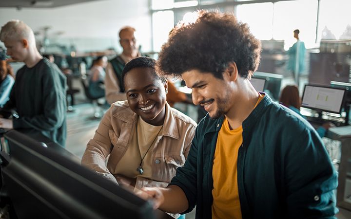 Man and a woman smiling and looking at desktop