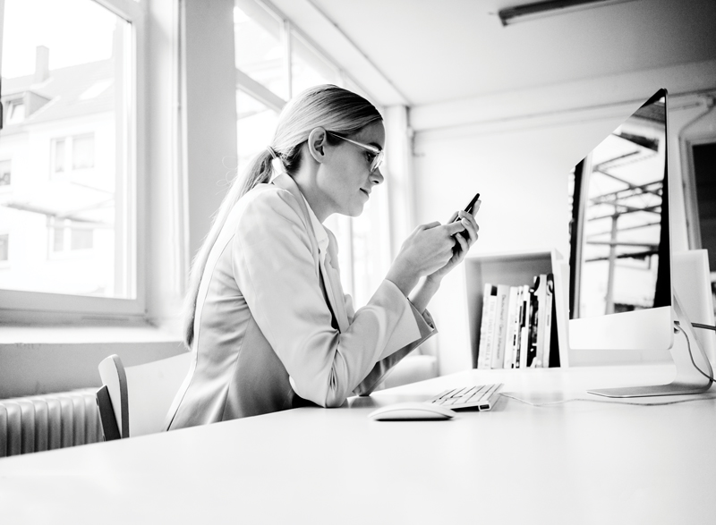 Woman using cell phone at desk