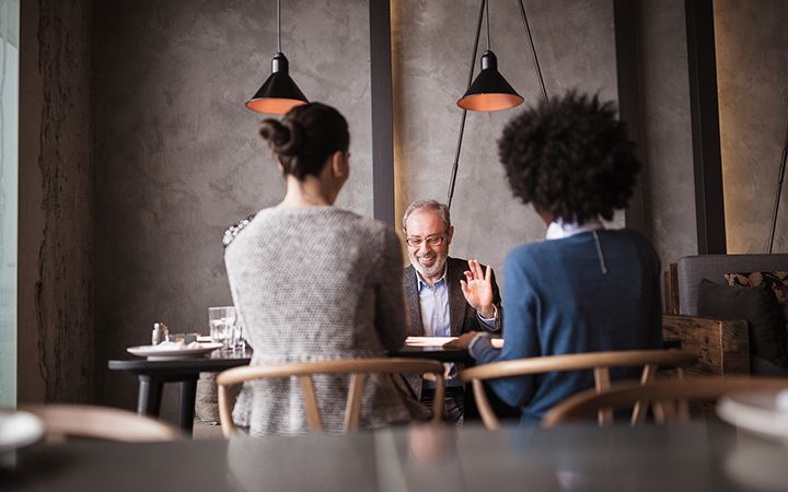  A man and two women talking and laughing in a cafeteria