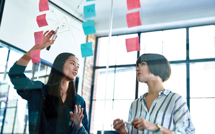 Two female coworkers discussing in a formal space