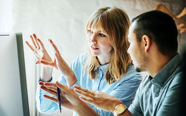 Two people gesturing to computer monitor