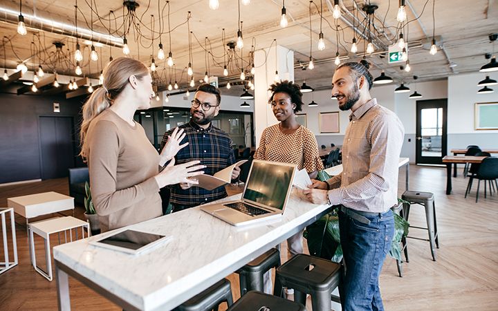 Colleagues standing around table discussing public relations