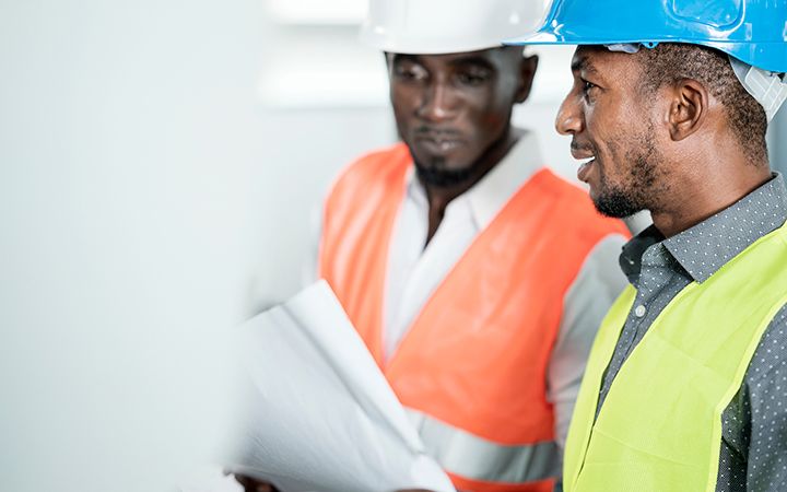two males with hardhats discussing design plans