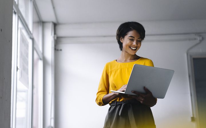 Women holder her laptop up, looking at it and smiling